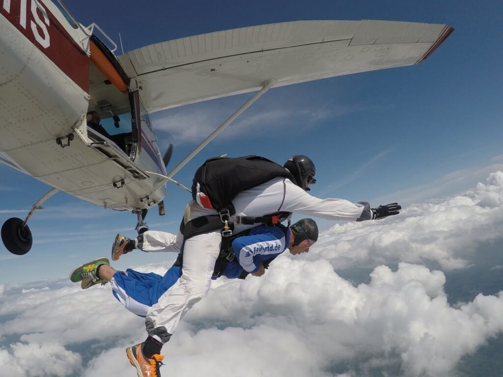 Exciting tandem skydive adventure captured in midair, above the clouds.